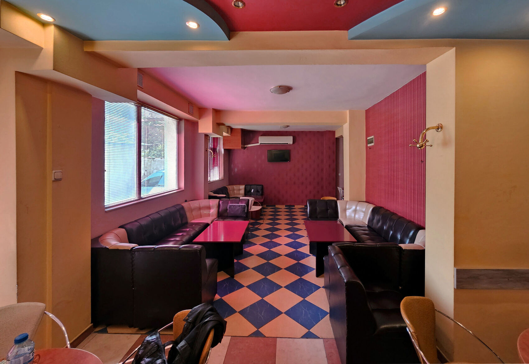 The dining room before: a pink-and-blue ceiling, dark banquettes and a diamond floor.