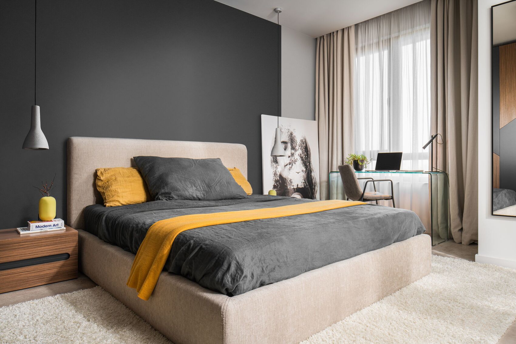 Schlafzimmer: dunkle Wand, beiges Bett und Schreibtisch am Fenster.