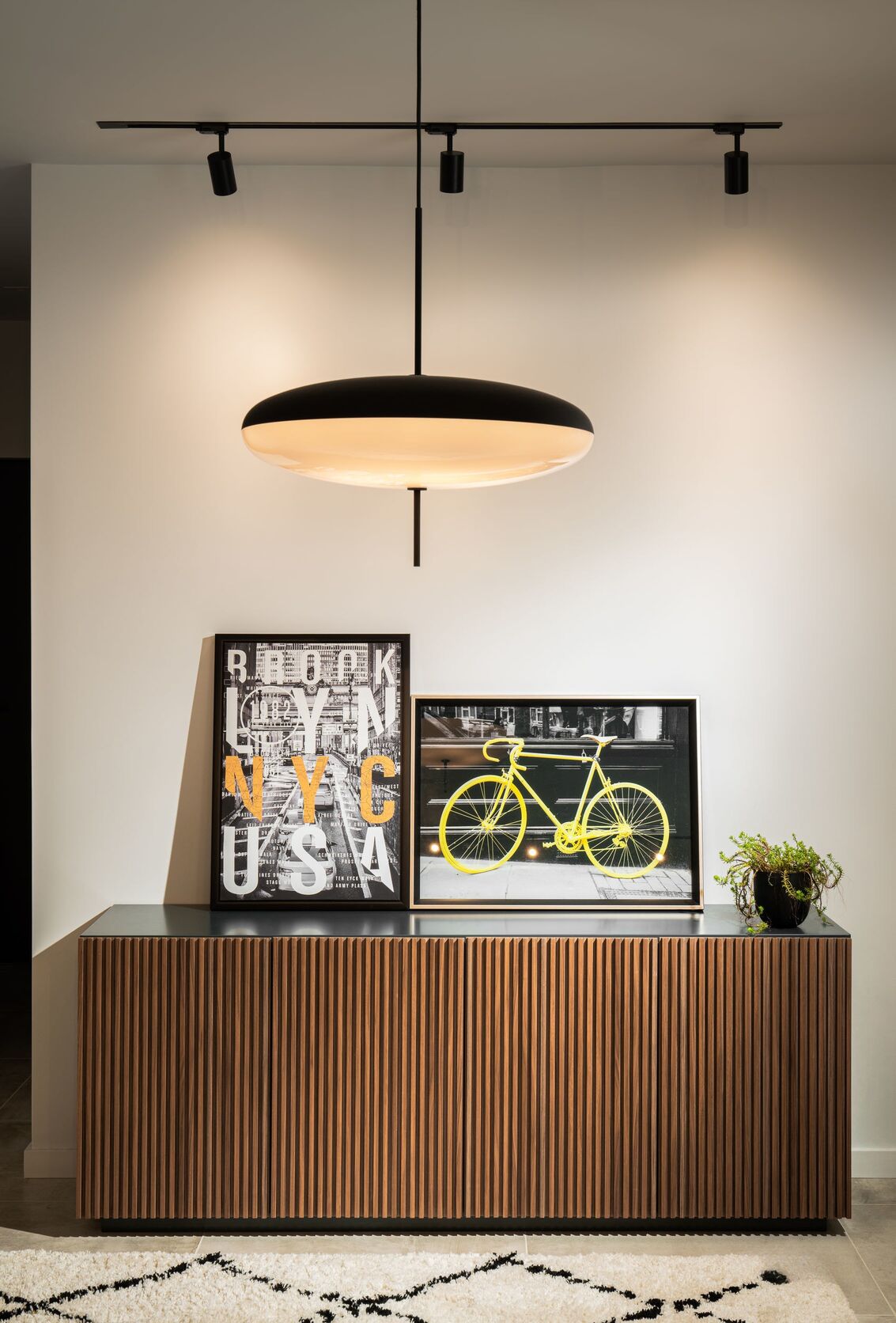 Enfilade de noyer, suspension en disque et affiches jaunes.
