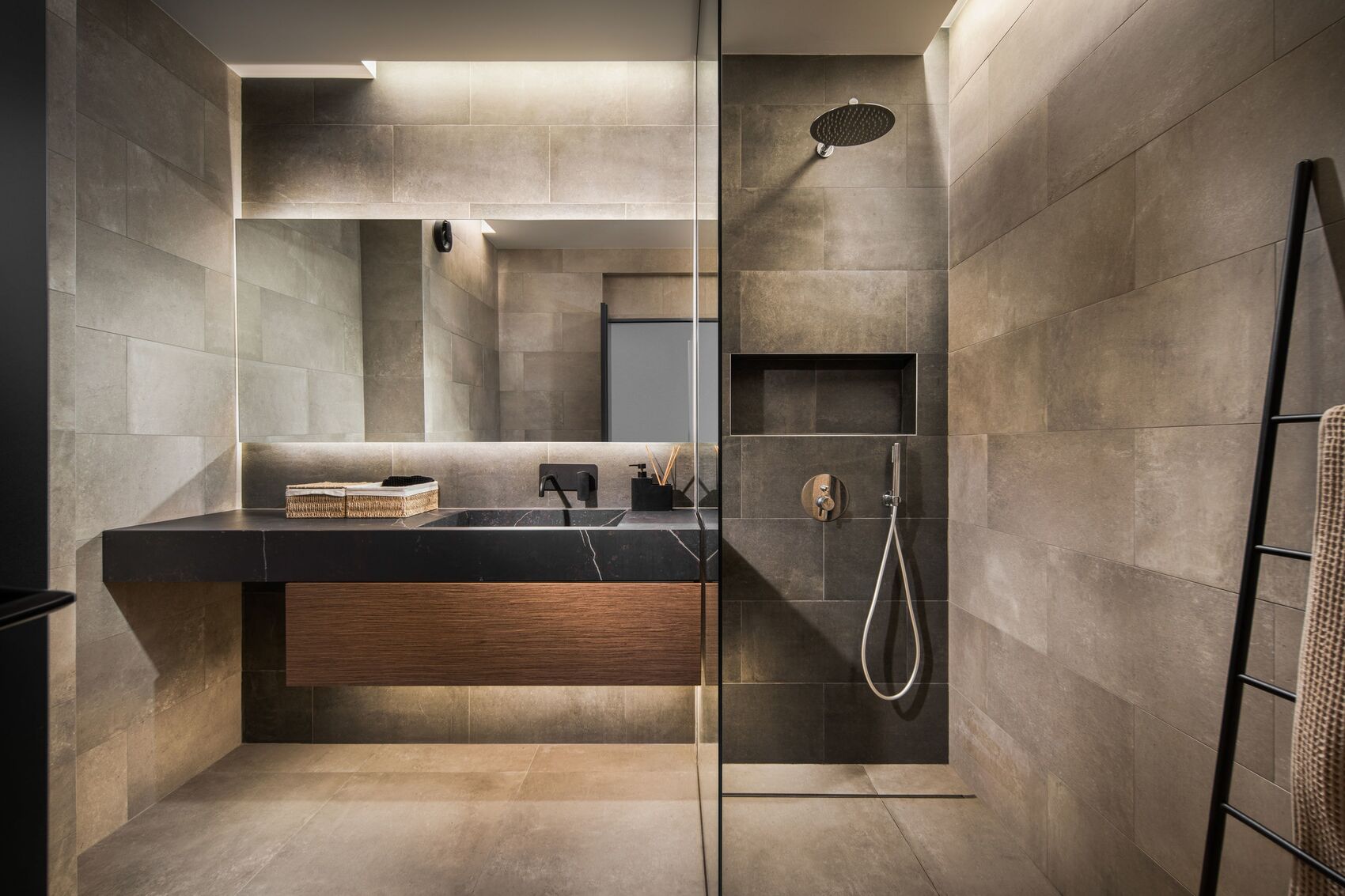 Bathroom with stone tiles, a black basin and a glazed shower.