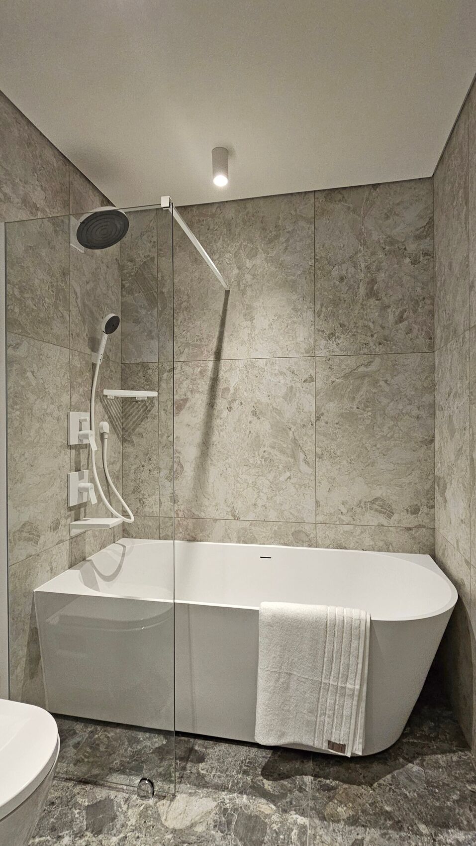 Eine Badewanne hinter einer Glaswand in einem Steinbad.