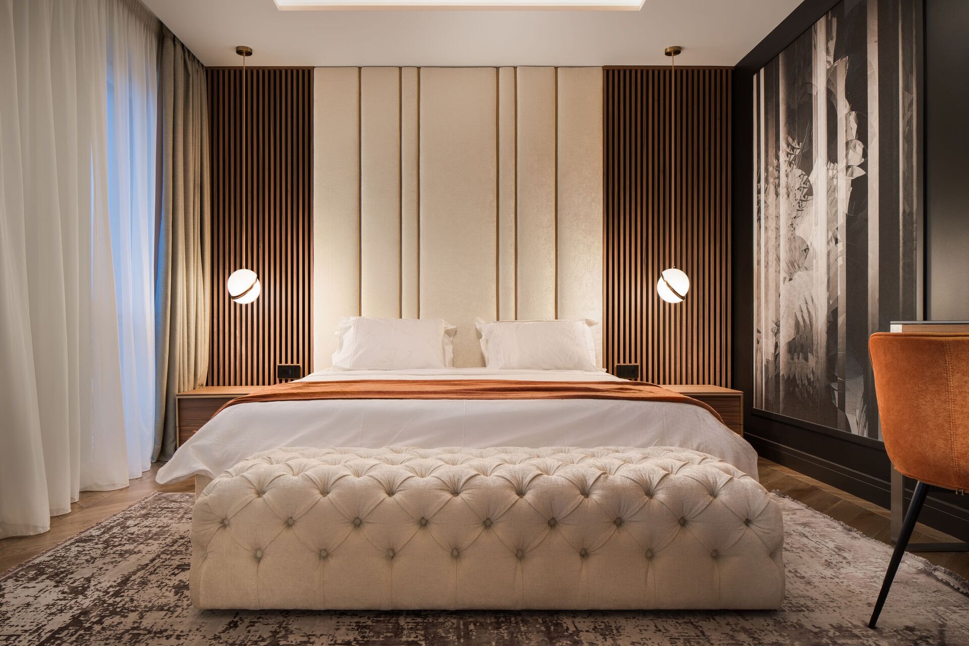 Chambre principale avec une tête de lit à lames symétrique et un banc capitonné.