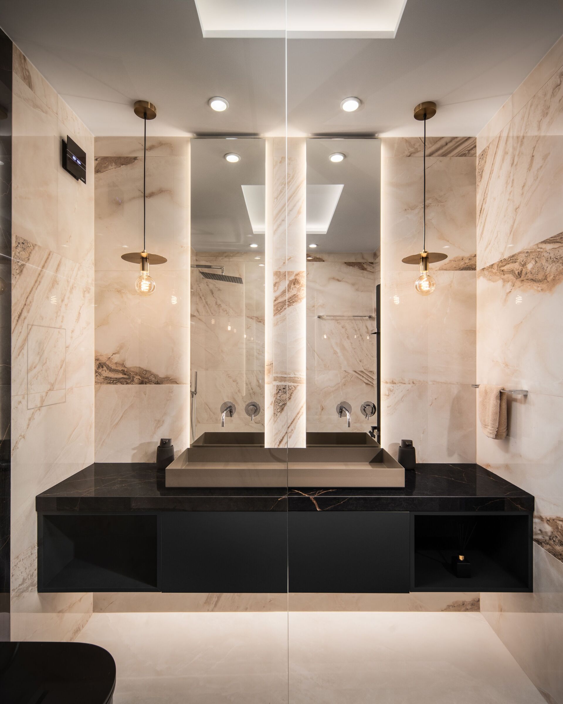 Meuble vasque de la salle de bain principale : long vasque, plan de marbre noir, hauts miroirs et suspensions de laiton.
