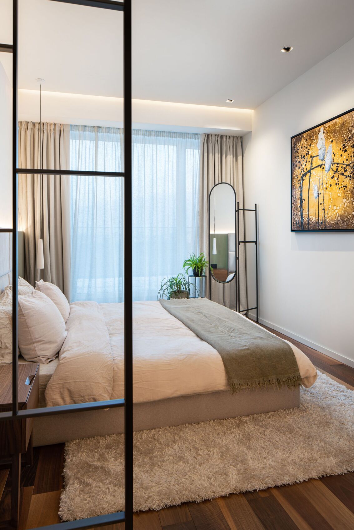 Schlafzimmer durch das Gitter zu Spiegel und Gemälde.