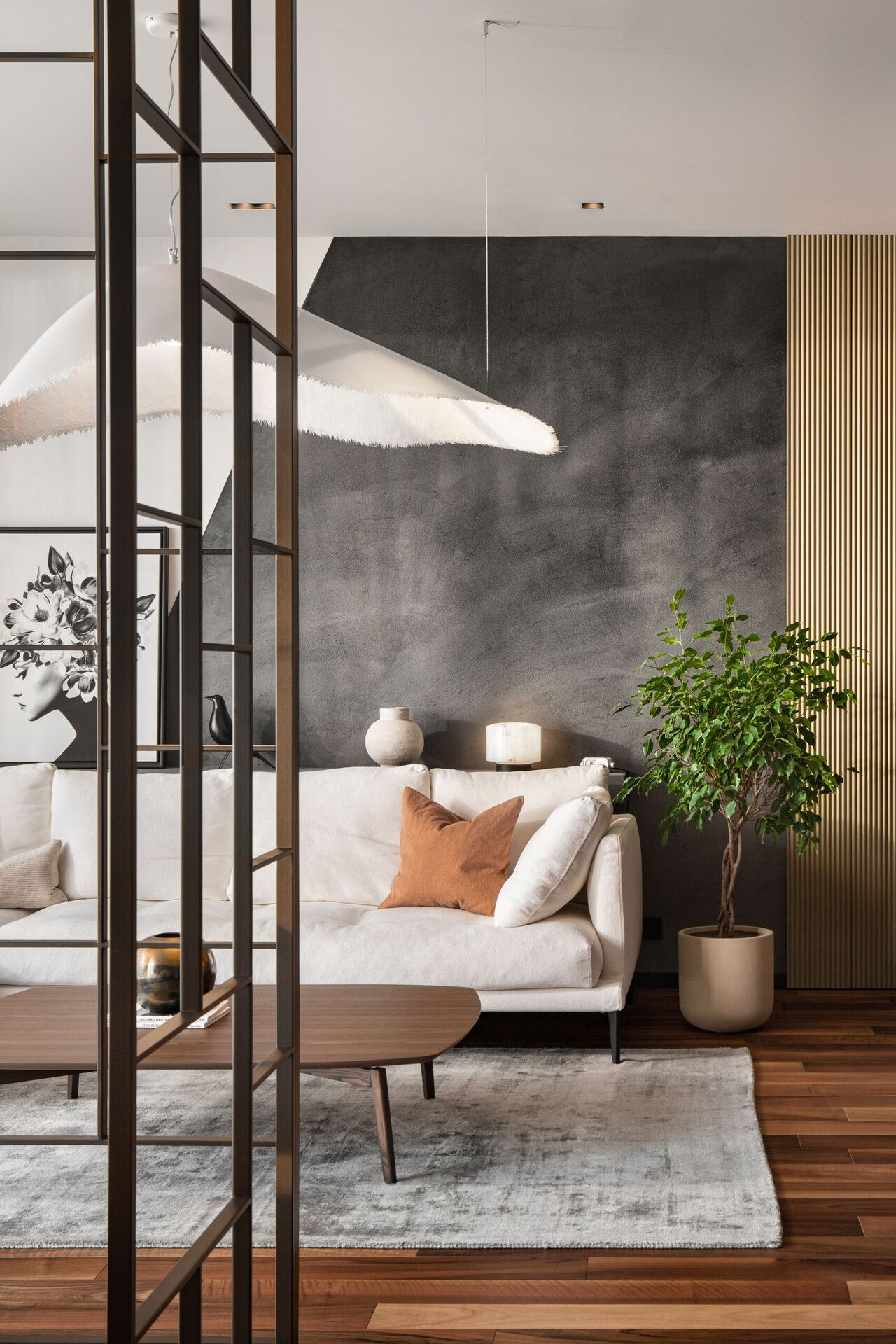 Ein Blick durch ein bronzenes Metallgitter auf Sofa und graue geometrische Wand.