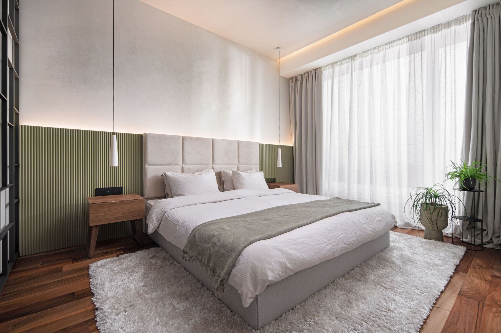 Schlafzimmer mit Kopfteil, Salbeipaneel und Fenster.