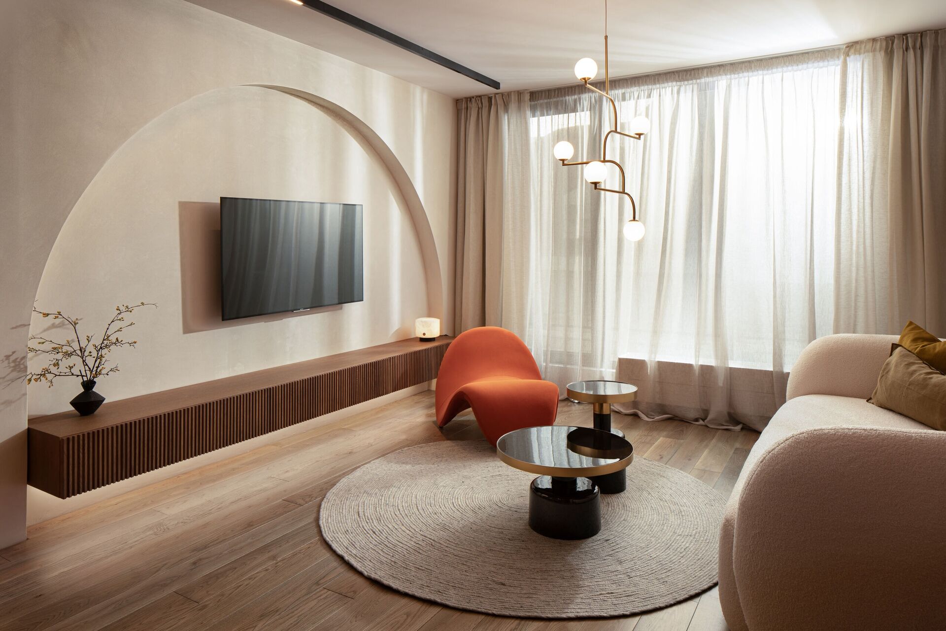 Living room toward the television vault, the orange chair and a round rug.